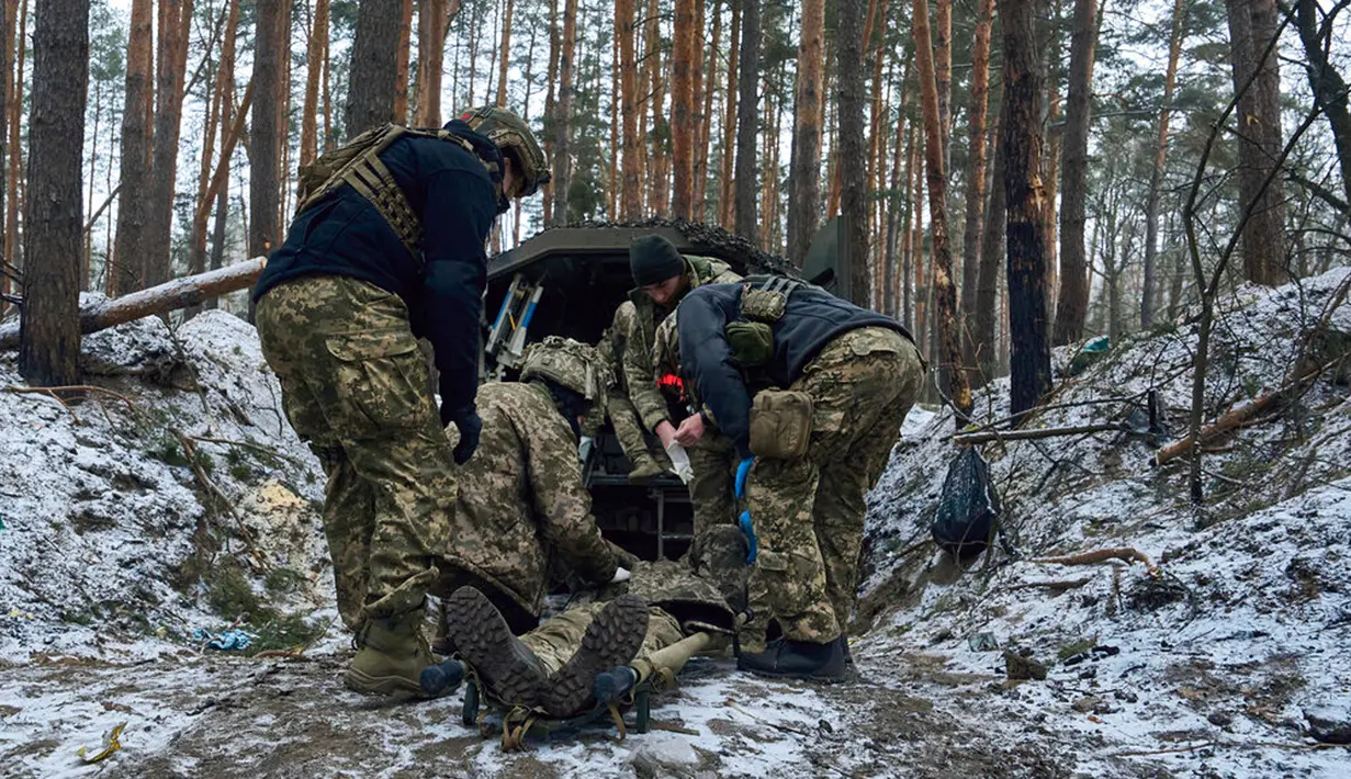 Petugas medis militer memberikan pertolongan pertama kepada seorang tentara yang terluka parah dekat Kremenna di wilayah Luhansk, Ukraina, 16 Januari 2023. Hingga saat ini pejabat Ukraina menolak untuk mengonfirmasi jumlah korban dalam perangnya dengan Rusia, setelah ketua Komisi Uni Eropa pada akhir November 2022 lalu memperkirakan bahwa "lebih dari 20.000 warga sipil dan 100.000 tentara Ukraina telah tewas di Ukraina hingga saat ini." (AP Photo/LIBKOS)
