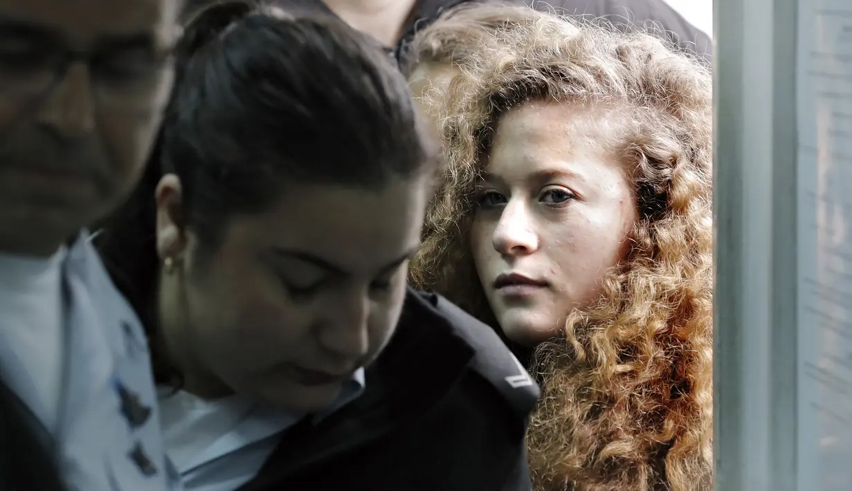 Ahed Tamimi dikawal petugas keamaan Isreal saat tiba di pengadilan militer Israel di penjara Ofer, Israel (13/2). Ahed Tamimi dikenai dakwaan atas 12 pelanggaran, termasuk menyerang pasukan keamanan dan menghasut kekerasan. (AFP/Thomas Coex)