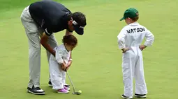 Pegolf Bubba Watson dari AS membantu putrinya Dakota putt saat mengikuti Masters Par 3 Tournament di Augusta National Golf Club, Georgia, (5/4). Anak-Anak ini menunjukkan keterampilannya bermain golf bersama orang tuanya. (Harry How/Getty Images/AFP)