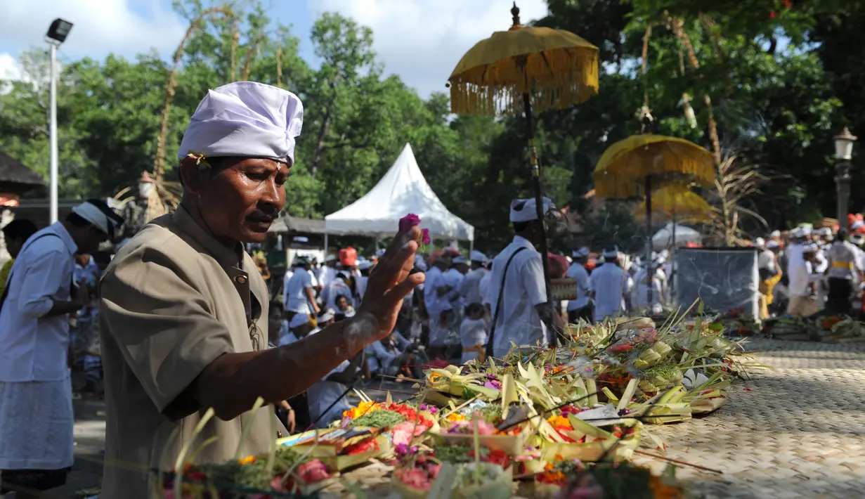 Umat Hindu meletakkan sesajen saat hendak berdoa selama perayaan Kuningan di sebuah pura di Pulau Serangan, Denpasar, Bali, Sabtu (20/2). Kuningan merupakan hari terakhir dari perayaan Galungan. (AFP PHOTO/SONNY Tumbelaka)