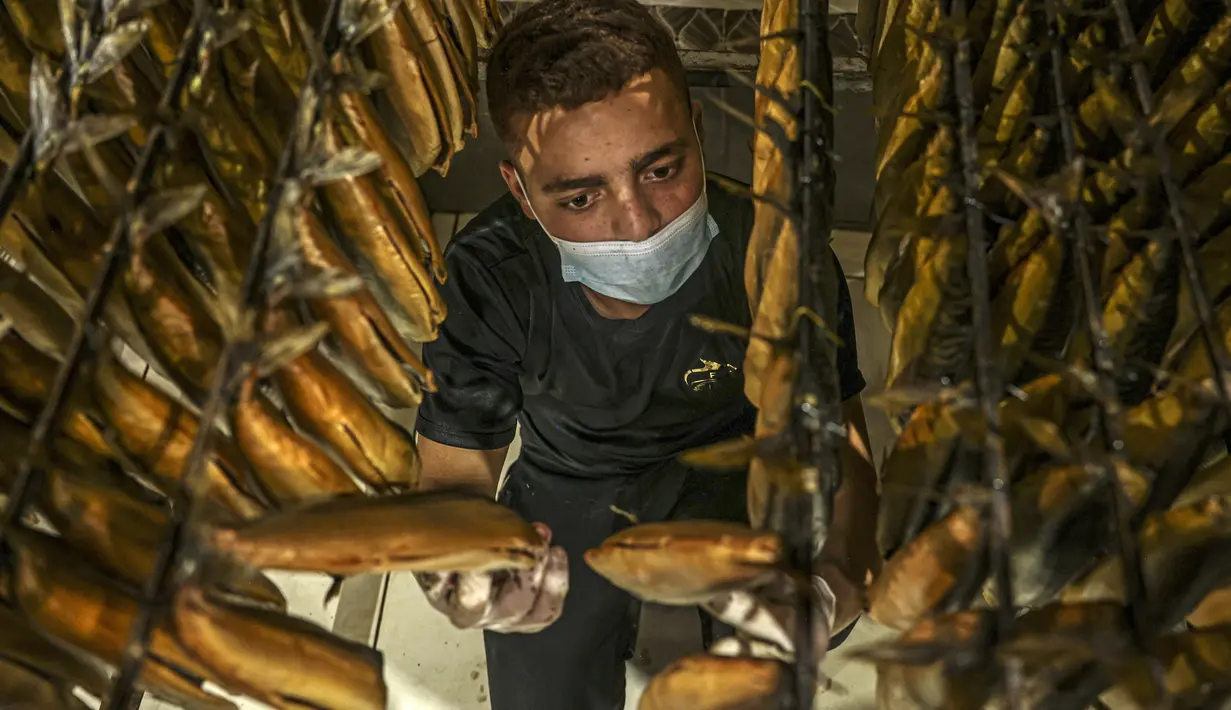 Seorang pekerja Palestina mengatur ikan asap di sebuah pabrik di Rafah di Jalur Gaza selatan pada 9 April 2023 untuk dijual di pasar menjelang liburan Idul Fitri yang menandai berakhirnya bulan puasa Ramadhan. (Photo by SAID KHATIB / AFP)