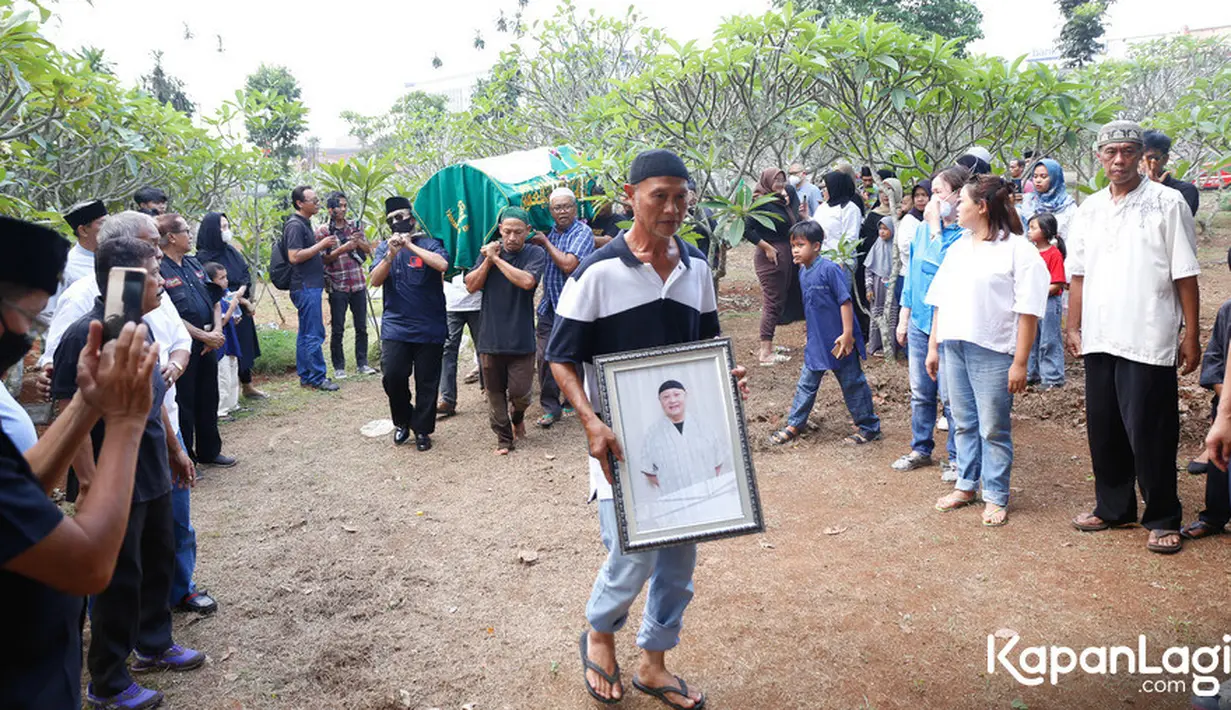 Setelah dimandikan dan disalatkan, jenazah di bawa ke TPU Parung Bingung, Jawa Barat. Turun dari mobil ambulance, digotong beberapa orang pria.Tampak seorang pria membawa foto Koh Ahong berjalan di depan iringan jenazah.  [Foto: Bayu Herdianto/KapanLagi.com]