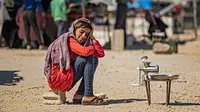 Seorang gadis Suriah yang terlantar menunggu pelanggan membawa buncis untuk digiling selama bulan suci Ramadan di kamp Washukanni untuk para pengungsi internal di provinsi Hasakeh di timur laut Suriah, (10/5/2020). (AFP/Delil Souleiman)