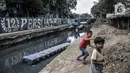 Anak-anak bermain di sekitar Kali Sentiong, Kecamatan Johar Baru, Rabu (22/9/2021). Pengerukan lumpur ini merupakan bagian dari program normalisasi guna memperdalam aliran Kali Sentiong. (merdeka.com/Iqbal S. Nugroho)