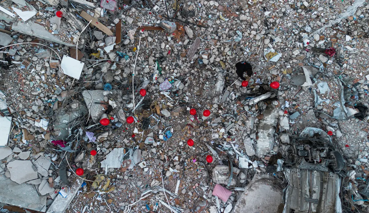 Foto udara menunjukkan Ogun Sever Okur, pria Turki berusia 38 tahun menggantung balon di atas puing-puing bangunan yang runtuh di Antakya, Turki selatan, setelah gempa berkekuatan 6,4 yang melanda pada 20 Februari, dua minggu. setelah gempa berkekuatan 7,8 melanda dekat Gaziantep dan telah menewaskan lebih dari 44.000 orang. Balon itu merupakan "mainan terakhir" dari anak-anak yang meninggal saat gempa yang menghancurkan kota Turki selatan ini, jelas Ogun Sever Okur, penulis hadiah anumerta ini. (AFP/Sameer Al-Doumy)
