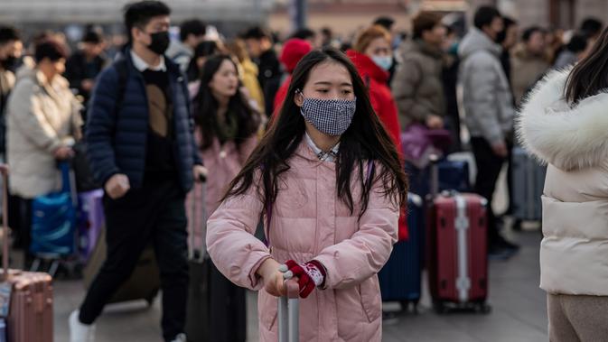 Orang-orang mengenakan masker penutup mulut setibanya di stasiun kereta api Beijing untuk mudik Tahun Baru Imlek pada Selasa (21/1/2020). Virus mirip SARS yang menyebar ke seluruh wilayah China dan mencapai tiga negara Asia ternyata dapat menular dari satu orang ke orang lain. (NICOLAS ASFOURI/AFP)