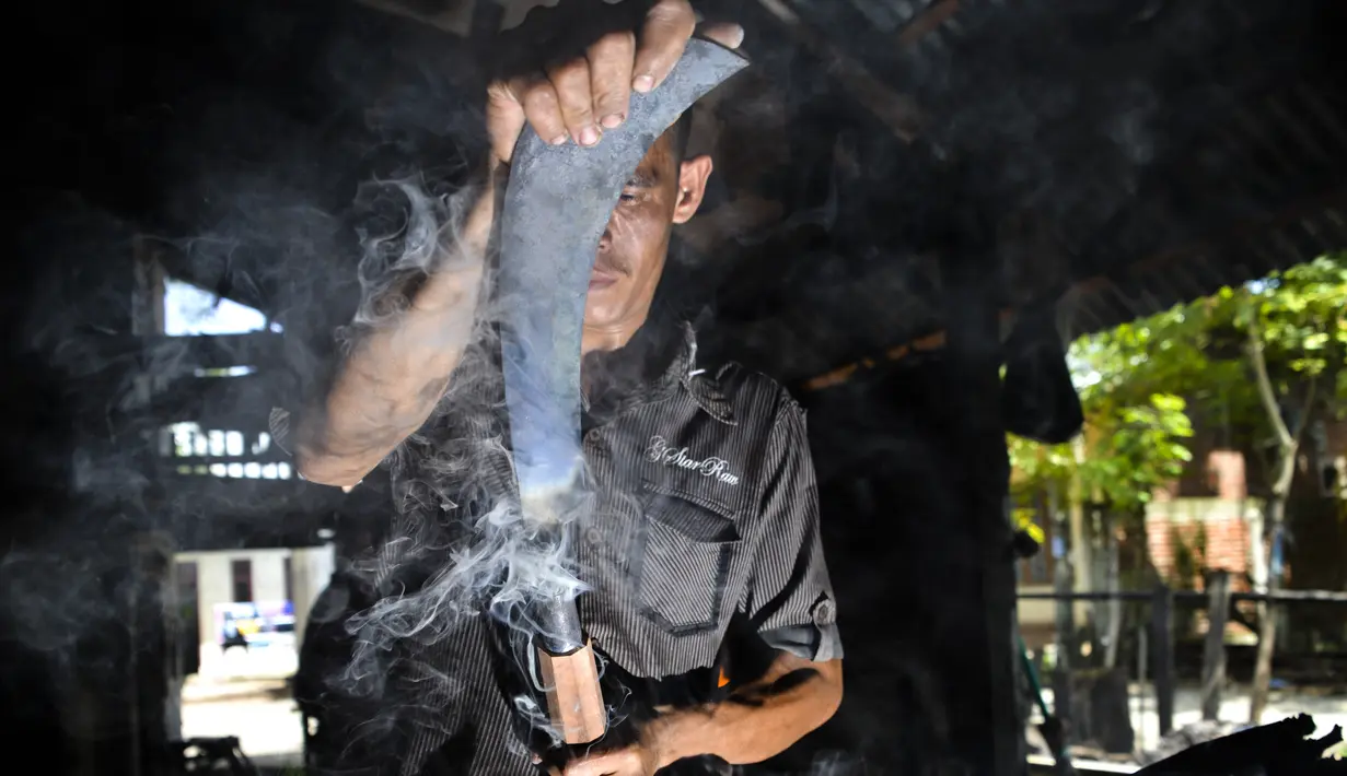 Seorang pandai besi saat menyelesaikan pembuatan pisau di bengkel tradisional di Darul Imarah, provinsi Aceh (4/11/2019). Usaha kerajinan pandai besi masih tetap bertahan di Kabupaten Aceh Besar di tengah maraknya produk pabrikan. (AFP Photo/Chaideer Mahyuddin)