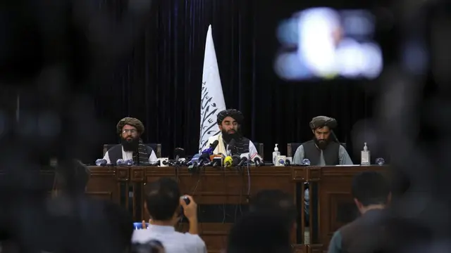 Zabihullah Mujahid berjanji akan menghormati hak-hak perempuan di depan bendera Taliban pada konferensi pers pertamanya di Kabul, Selasa (17/8/2021) (AP Photo/Rahmat Gul)