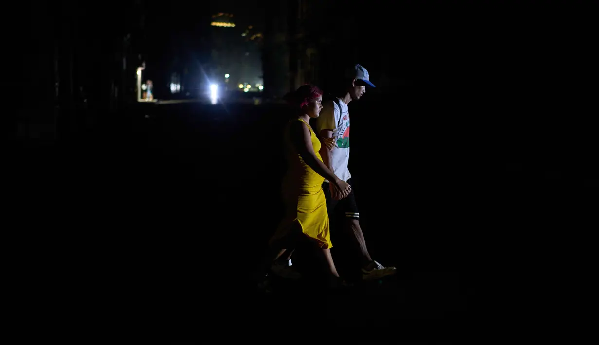 Orang-orang menyeberang jalan saat pemadaman listrik di Havana, Kuba, Rabu 4 Maret 2026. Pemadaman listrik besar melanda dua pertiga wilayah Kuba, termasuk ibu kota Havana. (AP Photo/Ramon Espinosa)