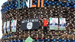 Poster para politisi Sinn Fein dipajang di tumpukan palet kayu yang akan digunakan membuat api unggun di Ballymacash, Lisburn, Irlandia Utara (10/7). (AFP Photo/Paul Faith)