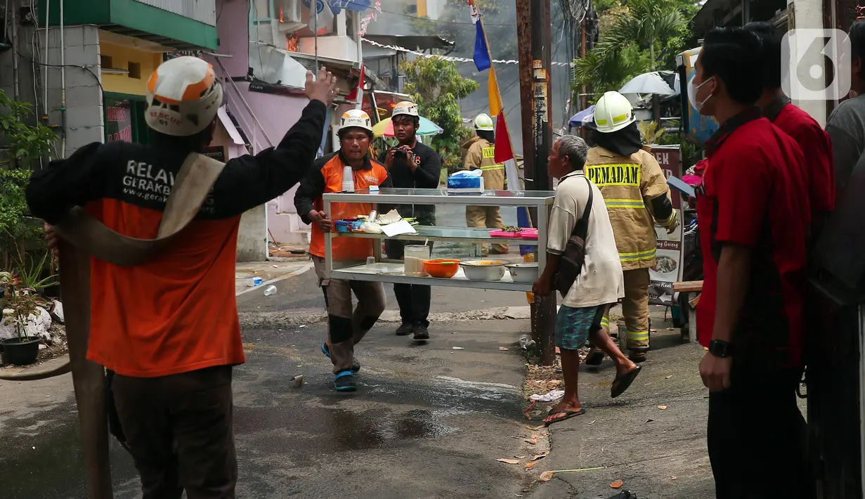 Warga bersama petugas mengevakuasi barang berharga saat terjadi kebakaran di kawasan padat penduduk di Jalan Simprug Golf II RT 4/8, Grogol Selatan, Kebayoran Lama, Jakarta Selatan, Minggu (21/8/2022). Hingga siang ini, petugas pemadam kebakaran bersama warga masih terus berusaha untuk memadamkan api. (Liputan6.com/Angga Yuniar)
