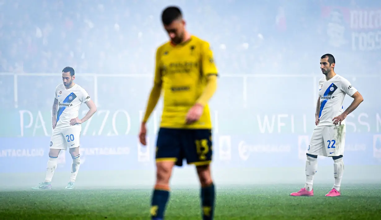 Pemain Inter Milan, Hakan Calhanoglu (kiri) dan Henrikh Mkhitaryan terlihat dalam kepulan asap saat laga lanjutan Liga Italia 2023/2024 melawan Genoa di Stadion Luigi Ferraris, Genoa, Italia, Sabtu (30/12/2023) dini hari WIB. (AFP/Piero Cruciatti)