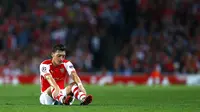 Gelandang Arsenal, Mesut Ozil, terduduk usai gagal memanfaatkan peluang mencetak gol ke gawang Besiktas di ajang play-off Liga Champions di Stadion Emirates, London, (28/8/2014). (REUTERS/Eddie Keogh)