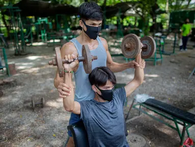 Dua pria berolahraga di gym luar ruangan di sebuah taman di Bangkok, Thailand, Rabu (10/6/2020). Kehidupan sehari-hari di ibukota kembali normal karena pemerintah Thailand terus melonggarkan pembatasan terkait dengan menjalankan bisnis di ibukota Bangkok. (AP Photo/Gemunu Amarasinghe)
