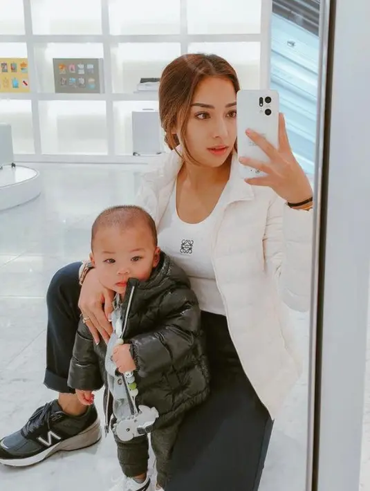 Nikita Willy tampil sporty memadukan puffer jacket putih, celana panjang hitam, dan sneakers warna senada. Gayanya ini kompak dengan baby Izz yang juga memilih outfit monokrom. [IG:indpriw].