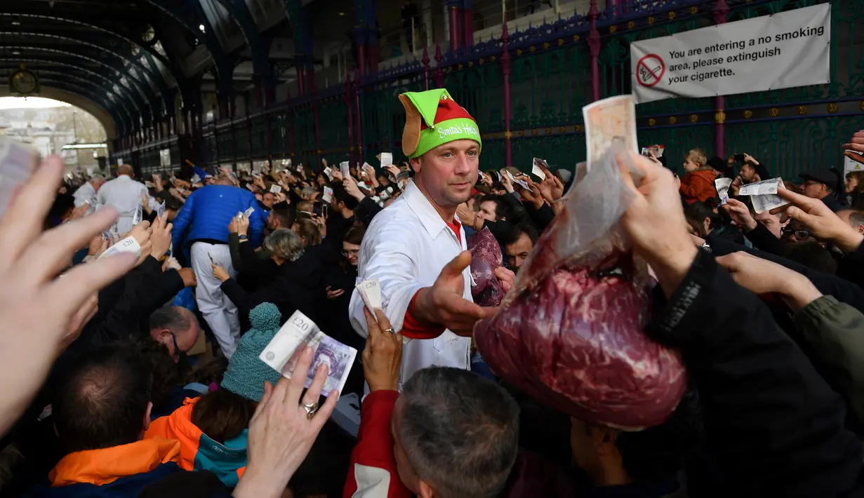 Seorang penjual melelang potongan daging kepada pembeli yang memegang uang selama lelang tahunan menyambut malam Natal di Smithfield Market, London, Selasa (24/12/2019). Dalam tradisi yang hadir sejak 1800-an, calon pembeli bisa menawar harga daging tersebut.  (DANIEL LEAL-OLIVAS / AFP)