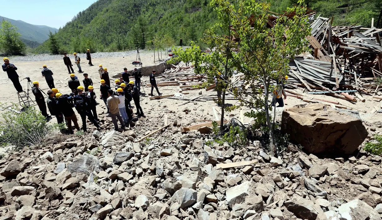 Pejabat Korea Utara dan wartawan asing berdiri dekat puing-puing setelah ledakan situs uji nuklir di Punggye-ri, Kamis (24/5). Sebelum dihancurkan, situs uji nuklir itu diyakini merupakan satu-satunya di dunia yang masih aktif. (Korea Pool/Yonhap via AP)