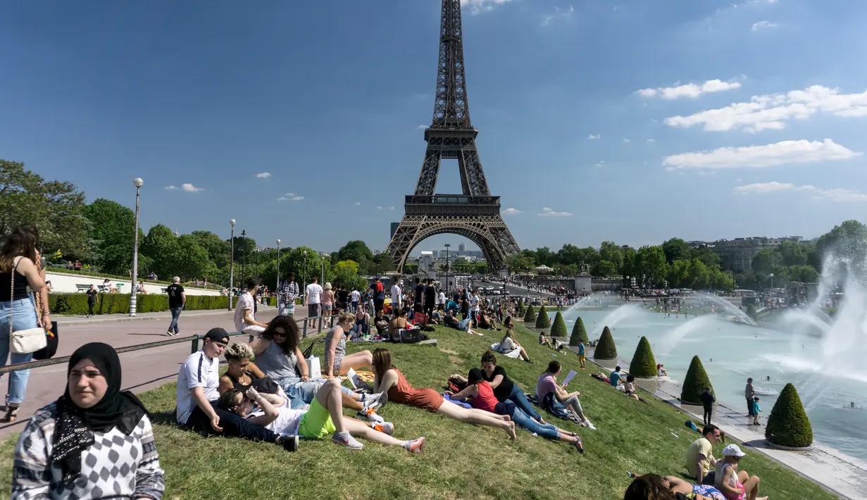 Warga berjemur di samping air mancur di Trocadero Esplanade, dekat Menara Eiffel, Paris (8/5). Tempat ini diciptakan untuk Pameran Internationale des Arts et Techniques dans la Vie Moderne (1937). (AFP Photo/Gerard Julien)