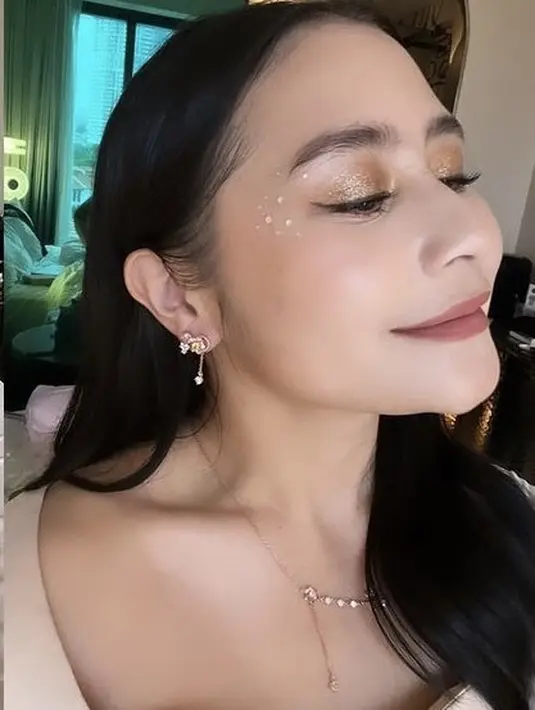 Ia juga tampil mengaplikasikan makeup warn dengan riasan mata coklat shimmer dan beberapa manik-manik di sisi mata. Blush on tips pink dan lipstik coklat matte. [@prillylatuconsina96]