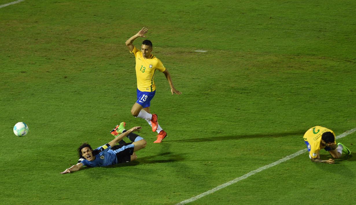 Striker Uruguay, Edinson Cavani, terjatuh saat perebutan bola dengan bek Brazil, Marquinhos. Kemenangan ini membuat Brasil semakin nyaman sebagai pemuncak klasemen sementara dengan koleksi 30 poin. (AFP/Pablo Porciuncula)