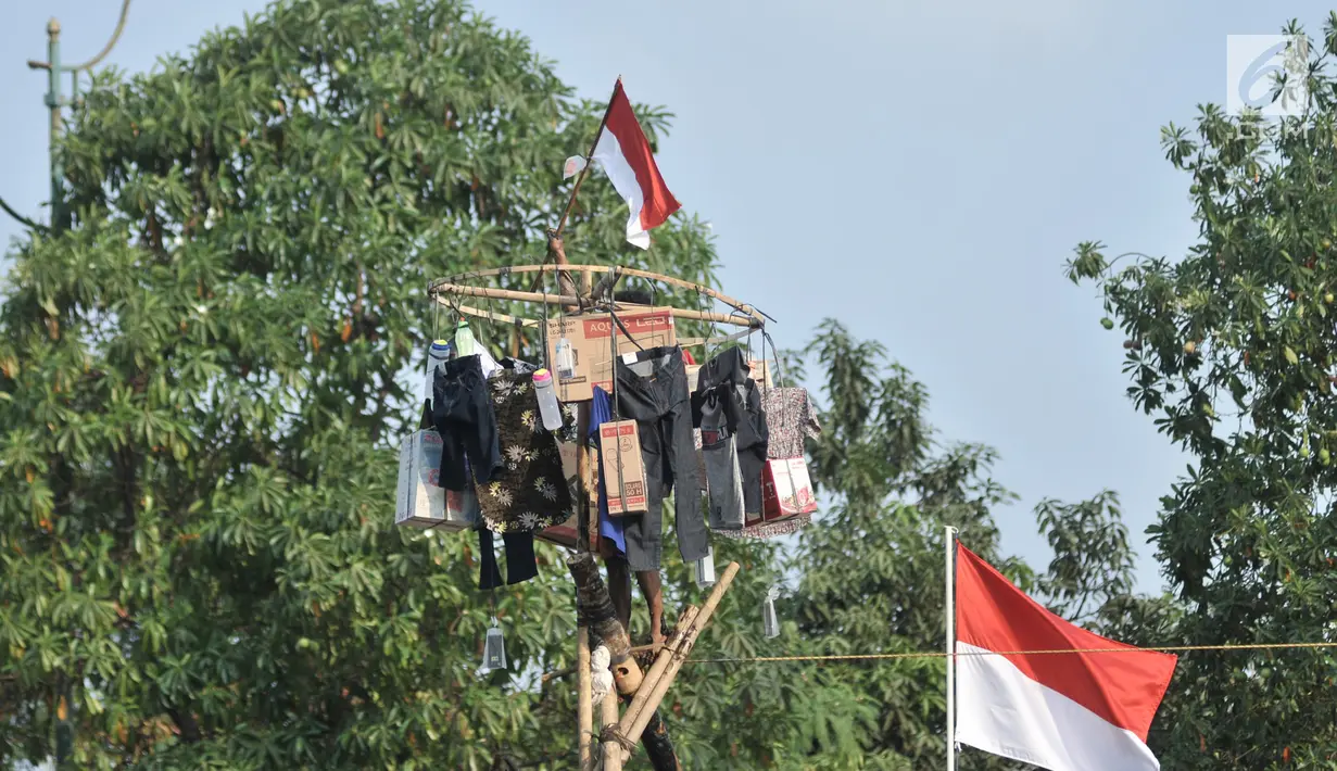Peserta mengibarkan Bendera Merah Putih saat berhasil menggapai puncak pinang 
dalam rangka HUT ke-74 RI di Kanal Banjir Timur, Jakarta, Sabtu (17/8/2019). (merdeka.com/Iqbal S. Nugroho)