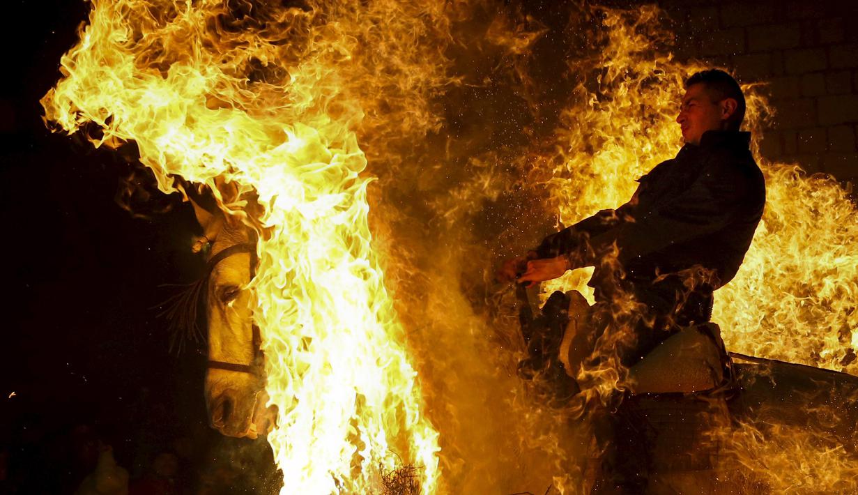 Seorang pria mengendarai kuda melintas kobaran api selama perayaan " Luminarias " di desa San Bartolome de Pinare, Spanyol, (16/1).  Tradisi sudah ada 500 tahun lalu di desa ini. (REUTERS / Susana Vera)
