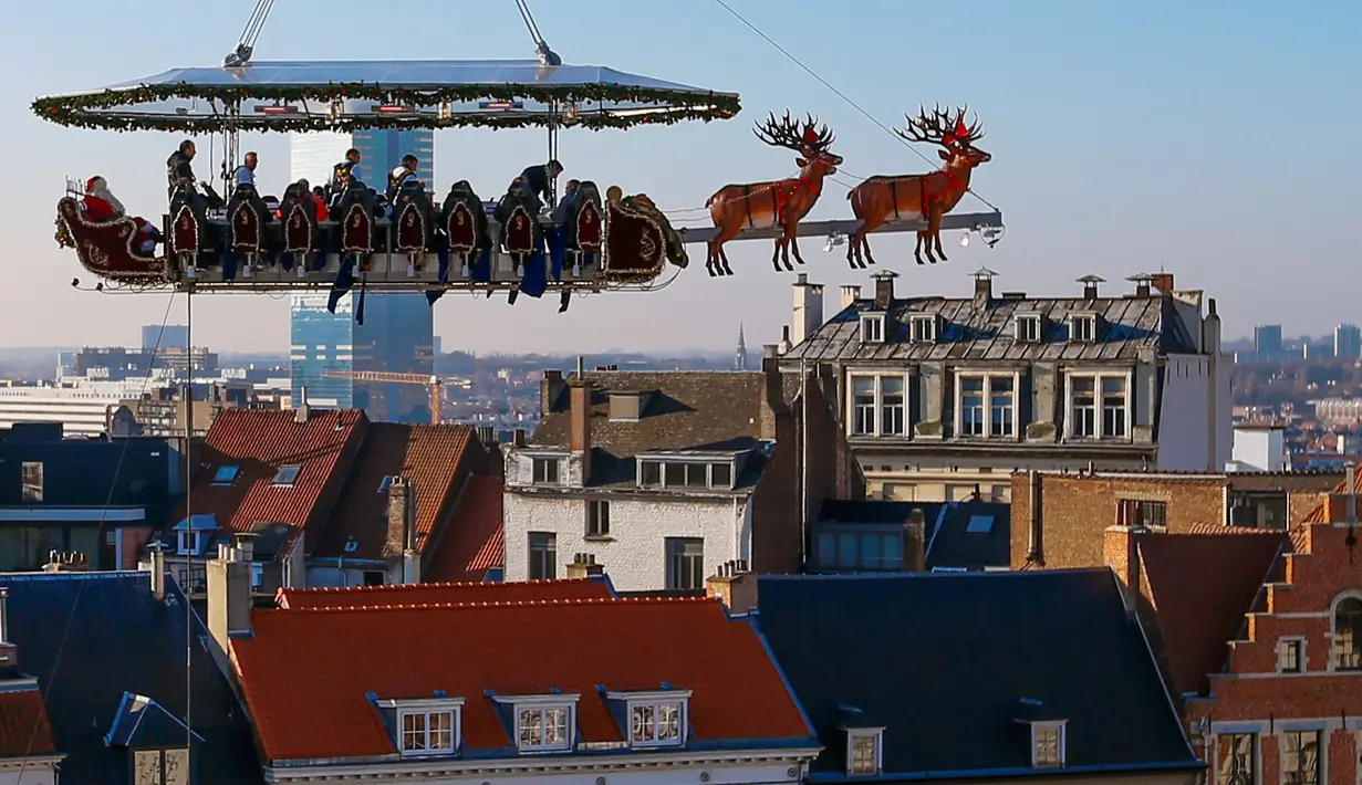 Para tamu menikmati makan malam di "Santa in the sky", yang diangkat dengan crane dan dihias menyerupai "Santa Sleigh" di Brussels, Belgia, 25 November 2016. Tempat ini didekorasi seperti kereta Santa Claus menjelang perayaan Natal. (REUTERS/Yves Herman)