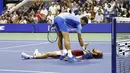 Petenis asal Serbia, Novak Djokovic (atas), menghampiri petenis asal Rusia Daniil Medvedev yang tergeletak di lapangan dalam pertandingan final US Open 2023 yang berlangsung di Arthur Ashe, New York, Senin (11/9/2023) pagi WIB. (AFP/Kena Betancur)