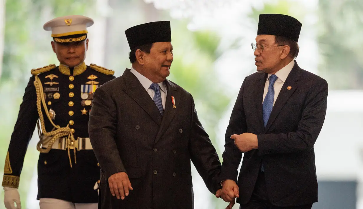 Presiden Republik Indonesia Prabowo Subianto (tengah) dan Perdana Menteri Malaysia Anwar Ibrahim (kanan) berjalan bersama menjelang pertemuan bilateral di Istana Kepresidenan, Jakarta pada 29 Juli 2025. (Yasuyoshi CHIBA/AFP)