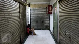 Seorang wanita duduk di antara ruko yang tutup di kawasan Glodok, Jakarta Barat, Jumat (4/11). Khawatir jadi sasaran anarkisme para pendemo, pedagang di kawasan Glodok memilih libur dan menutup toko. (Liputan6.com/Gempur M Surya)