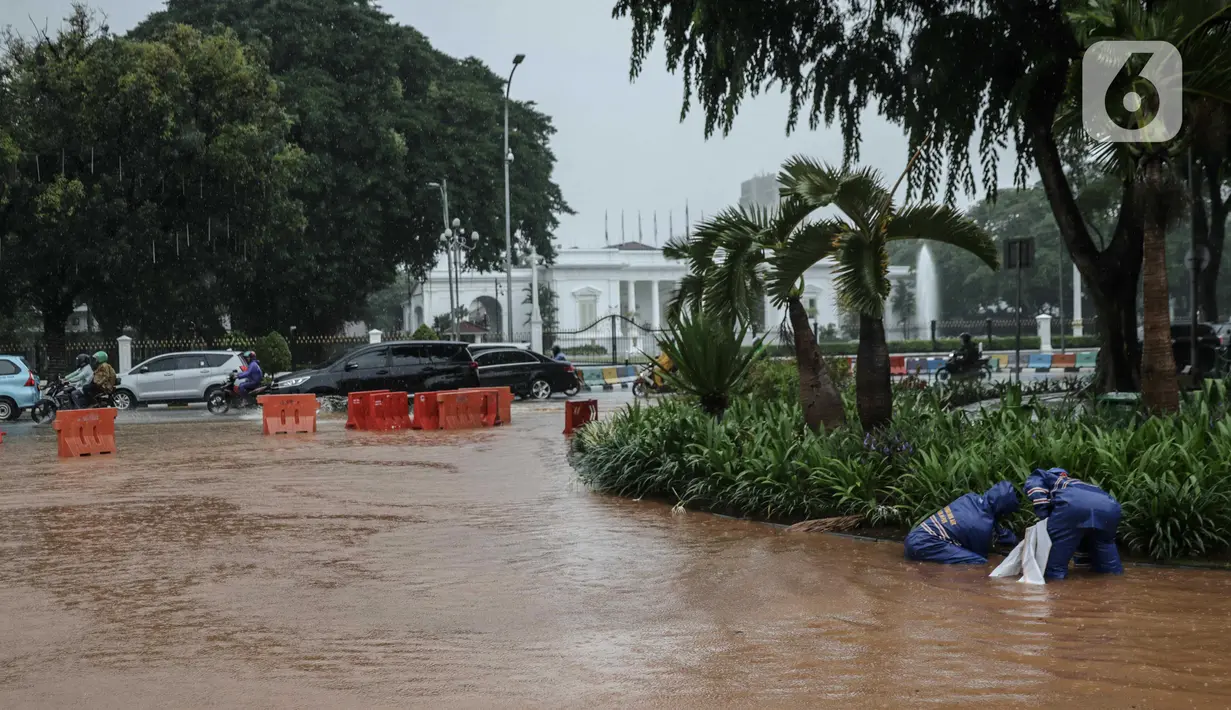 Petugas mengecek genangan air di Jalan Medan Merdeka Barat, Jakarta, Kamis (24/1/2020). Hujan deras yang mengguyur Jakarta sejak pagi tadi mengakibatkan genangan air di Jalan Medan Merdeka Barat. (Liputan6.com/Faizal Fanani)