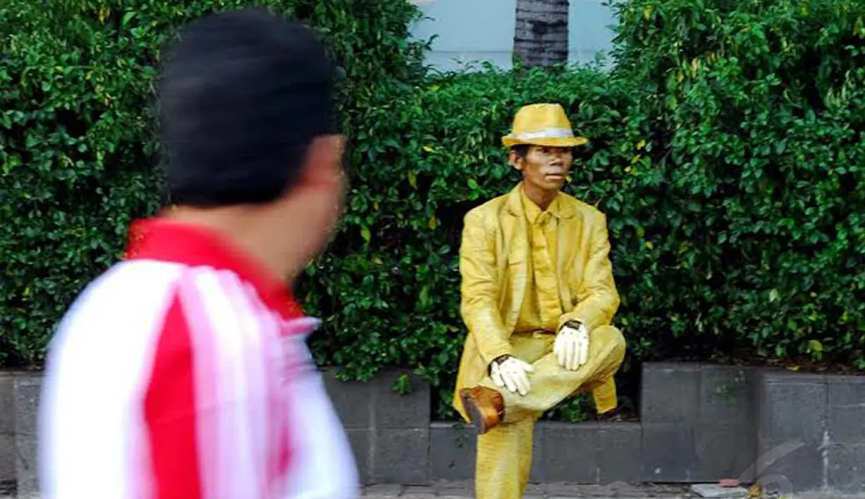 Manusia patung itu beraksi seolah-olah sedang duduk pada sebuah bangku yang tidak terlihat wujudnya (Liputan6.com/Miftahul Hayat)