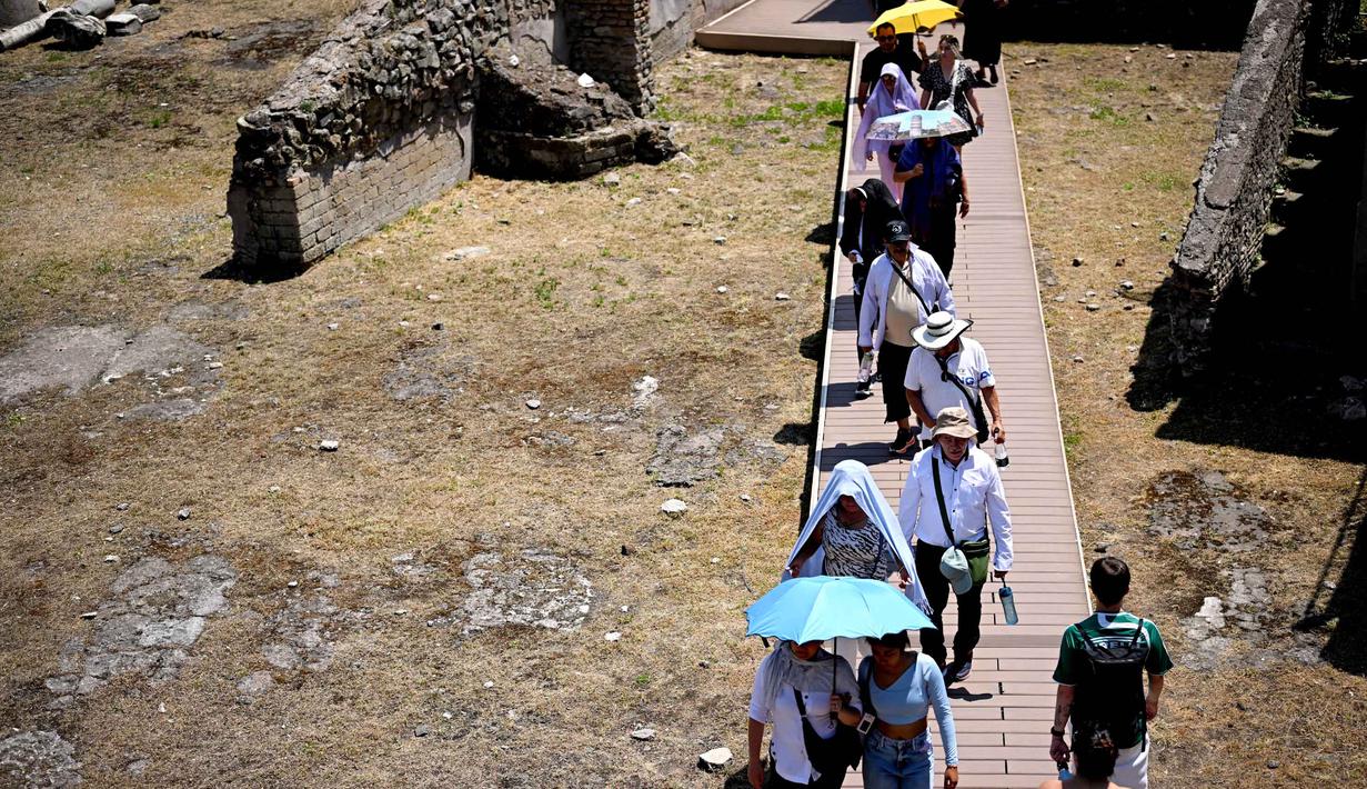 Orang-orang melindungi diri dari terik matahari dengan payung saat mengunjungi Forum di tengah gelombang panas awal musim di Roma pada Kamis 28 Mei 2026. (Tiziana FABI/AFP)