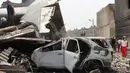 Sebuah mobil yang hangus terbakar tertimpa ekor pesawat Hercules C-130 yang jatuh di kawasan perumahan di Medan, Selasa (30/6/2015). Diperkirakan sekitar 50 penumpang berada dalam pesawat untuk melakukan rotasi tugas piket. (AFP PHOTO/ATAR)