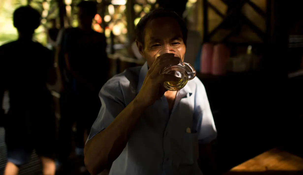 Pengunjung menikmati minikmati minuman beralkohol yang telah disimpan di dalam batang bambu selama beberapa bulan di Hutan Yibin, China pada 30 Juli 2016. (AFP Photo/Fred Dufour)