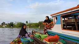 Para pedangan Pasar Terapung Lok Baintan menghampiri perahu kelotok pengunjung dengan sampan atau jukung (Liputan6.com/Pool/Kadek Arini)