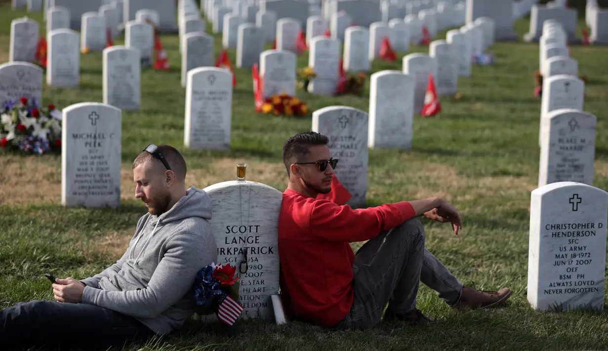 Tony Brown (kiri) dan Neil Thomas (kanan) mengenang teman mereka Sersan Scott Lange Kirkpatrick saat peringatan Hari Veteran, Arlington, Virginia, AS, Senin (11/11/2019). Rakyat AS memperingati Hari Veteran untuk menghormati mereka yang pernah bertugas di militer AS. (Alex Wong/Getty Images/AFP)
