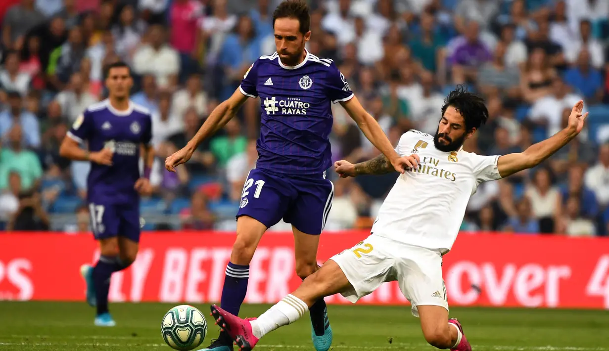 Gelandang Real Madrid, Isco, menekel gelandang Valladolid, Michel, pada laga La Liga di Stadion Santiago Bernabeu, Madrid, Sabtu (24/8). Kedua klub bermain imbang 1-1. (AFP/Gabriel Bouys)