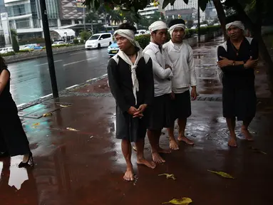 Empat warga Baduy berteduh ketika hujan mengguyur kawasan Bundaran HI, Jakarta, Selasa (6/9). Warga Baduy berjalan ratusan kilometer dari kampung mereka tanpa alas kaki dan sama sekali tidak menggunakan kendaraan bermotor. (Liputan6.com/Faizal Fanani)