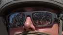 Para pengunjuk rasa yang memegang tanda dan bendera tercermin dalam kacamata yang dikenakan Garda Nasional California yang berdiri di luar Gedung Federal saat mereka memprotes operasi imigrasi federal di Los Angeles, Amerika Serikat pada 9 Juni 2025. (Apu GOMES/AFP)