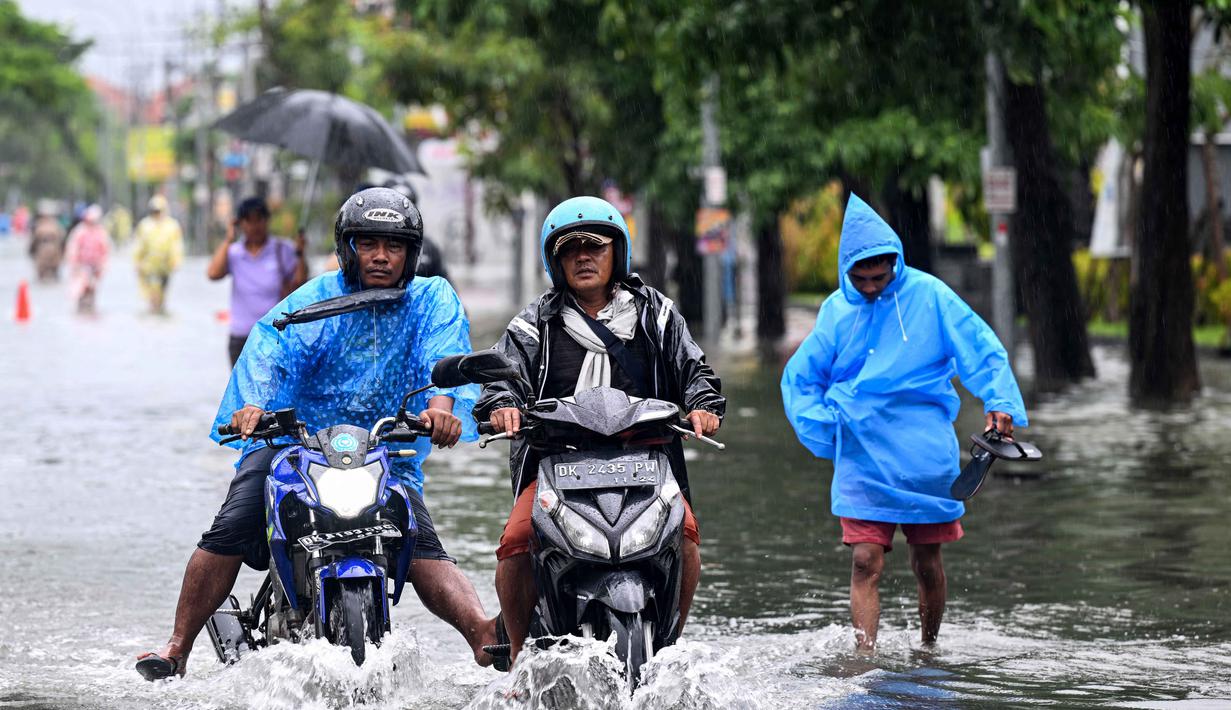 Beberapa kendaraan, baik sepeda motor maupun mobil ikut terendam dan tidak dapat melintas. Tampak dalam foto, para pengendara sepeda motor melaju melewati air di jalan yang tergenang banjir akibat hujan lebat di Legian Kuta, Denpasar, Bali, pada Selasa 24 Februari 2026. ((SONNY TUMBELAKA/AFP)