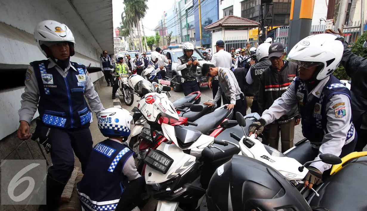 Petugas Dishub mencabut pentil kendaraan roda dua dalam operasi penertiban parkir liar di Pusat, Jumat (23/10/2015). Meskipun informasi penertiban diduga telah bocor, ratusan kendaraan yang parkir liar tetap ditertibkan. (Liputan6.com/Immanuel Antonius)