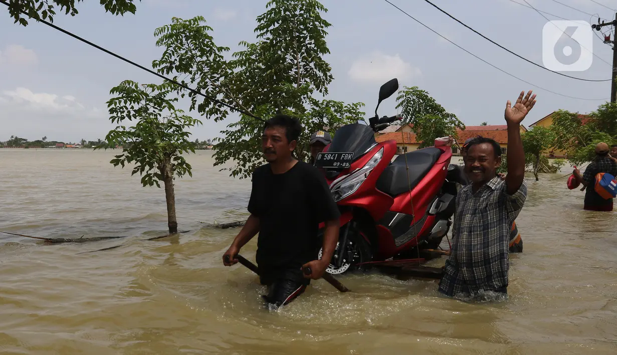 Warga membawa motor saat banjir di Desa Sukalaksana Kabupaten Bekasi, Jawa Barat, Senin (22/02/2021). Hujan dengan intensitas tinggi turun sejak Jumat, 19 Februari 2021 mengakibatkan air di aliran sungai meluap. (Liputan6.com/Herman Zakharia)