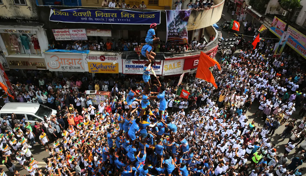 Pemuda India membentuk piramida manusia untuk memecahkan pot berisikan semacam susu dalam perayaan Festival Janmashtami di Mumbai, Senin (3/9). Acara tersebut dimaksudkan untuk menghormati upaya Khrisna mendapatkan mentega. (AP/Rafiq Maqbool)