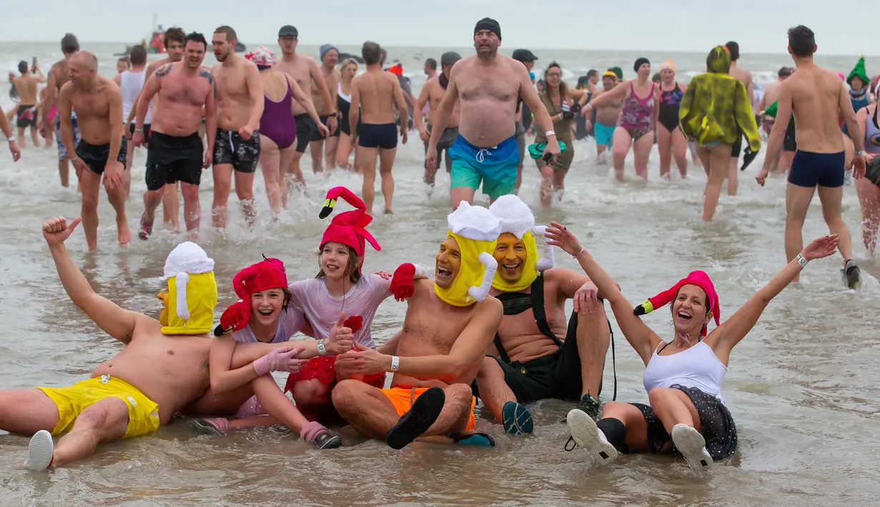 Orang-orang dengan kostum warna-warni menyerbu perairan Laut Utara  untuk merayakan akhir pekan pertama Januari 2020 di Ostend, Belgia, Sabtu (4/1/2020). Cuaca dingin tak menghalangi mereka untuk menceburkan diri ke laut yang merupakan salah satu tradisi tahun baru.  (NICOLAS MAETERLINCK/BELGA/AFP)