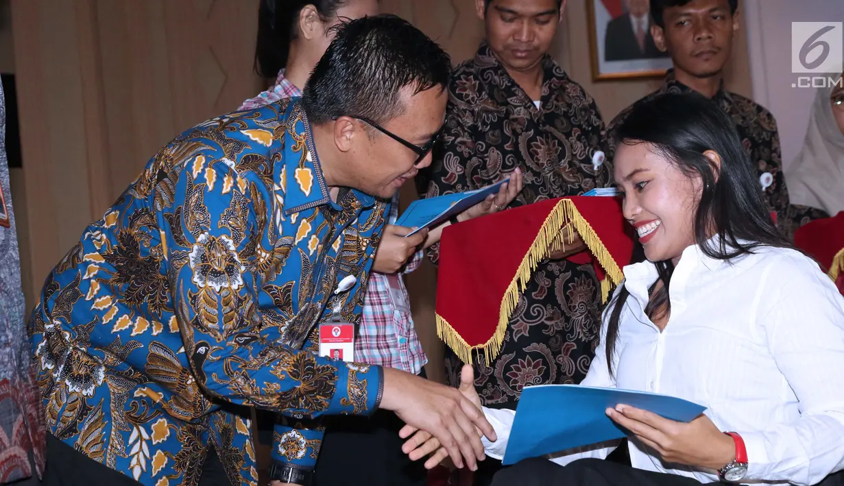Menpora Imam Nahrawi (kiri) menyerahkan SK CPNS kepada atlet powerlifting Indonesia, Ni Nengah Widiasih di Wisma Kemenpora, Jakarta, Selasa (2/4). 286 atlet berprestasi menerima SK pengangkatan sebagai CPNS di lingkungan Kemenpora. (Liputan6.com/Helmi Fithriansyah)