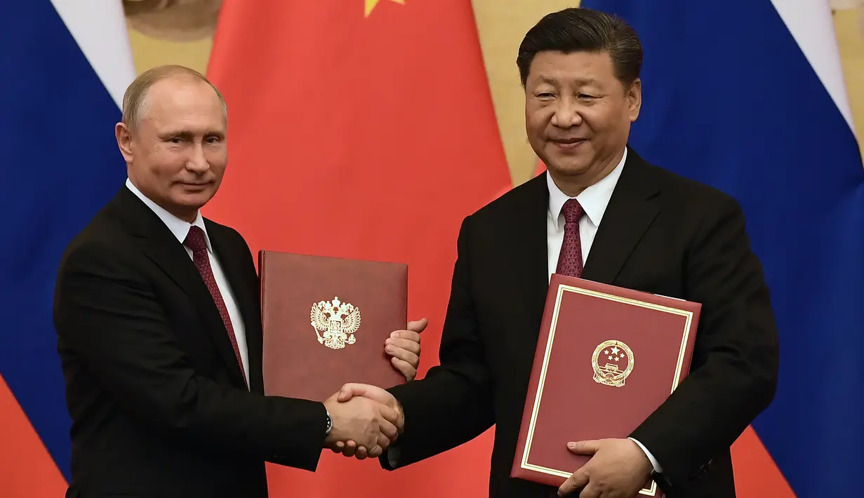 Presiden Rusia Vladimir Putin (kiri) bersalaman dengan Presiden China Xi Jinping saat upacara penandatanganan kerja sama di Beijing, China (8/6). Untuk kali ke-25 Presiden Rusia Vladimir Putin bertemu dengan Presiden Xi Jinping. (AFP/Pool/Nicolas Asfouri)