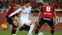 Gelandang Real Madrid, James Rodriguez, berusaha melewati kepungan pemain Real Mallorca pada laga La Liga Spanyol di Stadion Iberostar, Mallorca, Sabtu (19/10). Mallorca menang 1-0 atas Madrid. (AFP/Javier Reina)