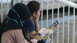 Pencari kerja melihat-lihat ponsel saat gelaran Job For Career Festival 2019 di area Stadion GBK, Jakarta, Selasa (5/3). Berdasarkan data BPS per Agustus 2018 sebanyak tujuh juta orang Indonesia menganggur. (Liputan6.com/Helmi Fithriansyah)