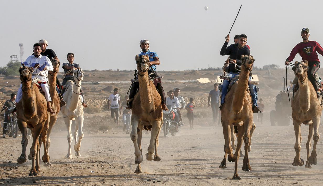 Tujuh peserta joki  bersaing dalam perlombaan balap unta lokal di Rafah, Jalur Gaza selatan (20/10/2019). Balapan unta ini menggunakan lintasan bekas landasan bandara Gaza yang sudah hancur di Rafah, Gaza selatan. (AFP Photo/Said Khatib)